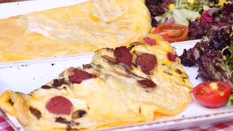 delicious omelette with sausage, mushrooms, and salad