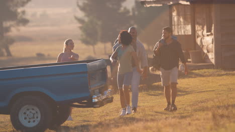 group of friends loading backpacks into pick up truck on road trip to cabin in countryside