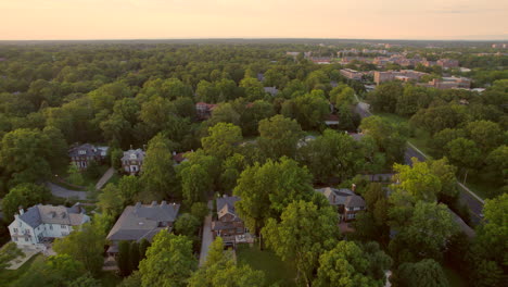 Pan left over beautiful Clayton neighborhood houses and trees with downtown skyline on horizon at sunset