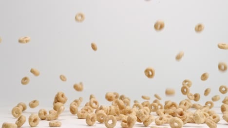 Vollkorn-Cheerio-Müsli,-Das-In-Zeitlupe-Auf-Einer-Weißen-Tischplatte-In-Einen-Stapel-Springt