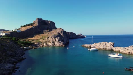 acropolis of lindos in rhodes, greece with houses and mediterranean sea during the day filmed with the drone