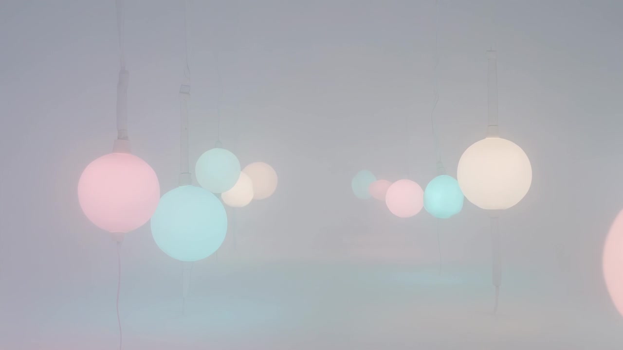 Panning camera revealing pastel pendant lights shifting focus and glow at gallery with thin cords