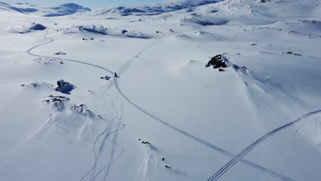 空中拍攝追蹤雪地摩托車穿過雪覆蓋的山地景觀