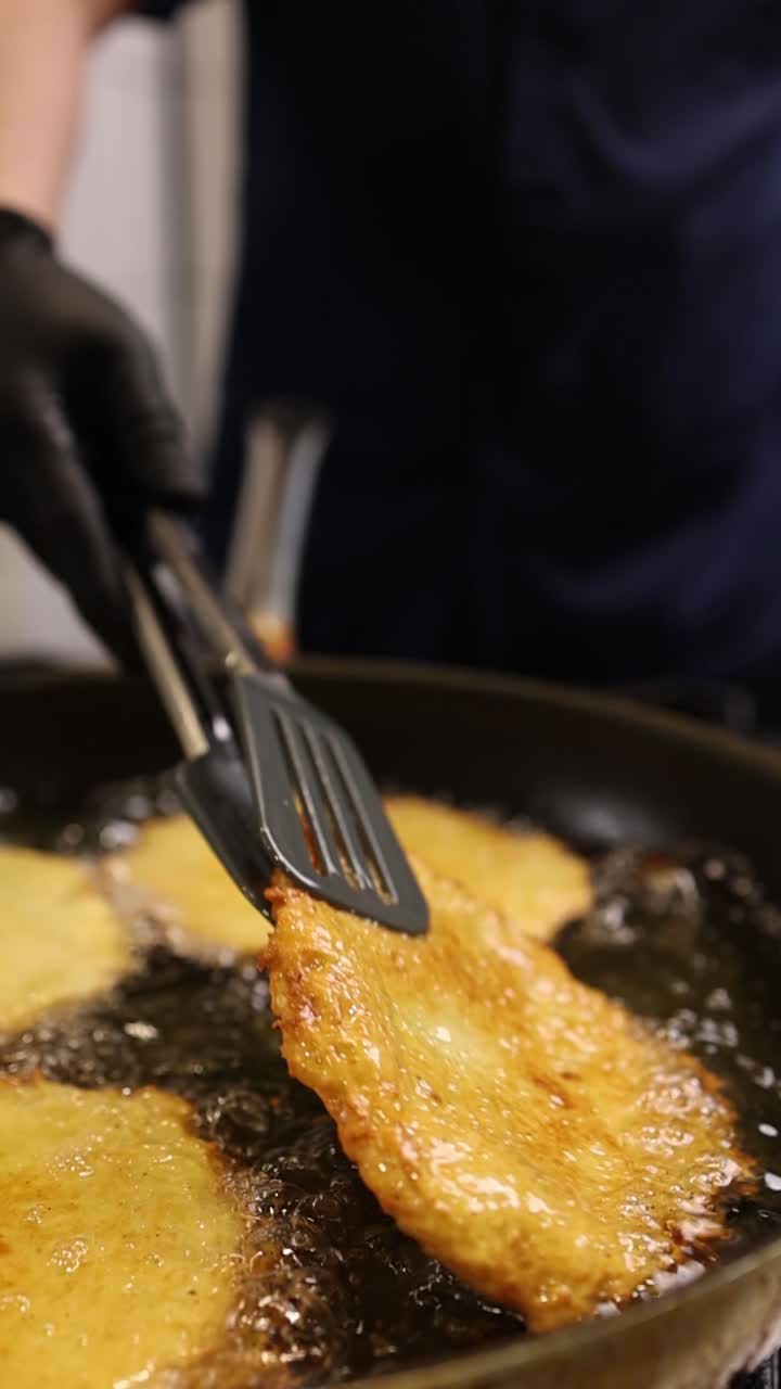 Primo piano di uno chef che frigge frittelle di patate dorate in olio bollente
