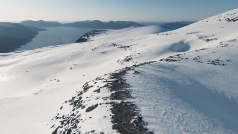 Volando-Por-La-Ladera-De-La-Montaña-Cubierta-De-Nieve-Con-Vistas-Majestuosas,-Antena-Fpv