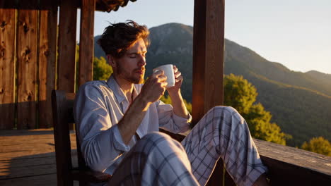 man drinking coffee on a porch with a mountain view