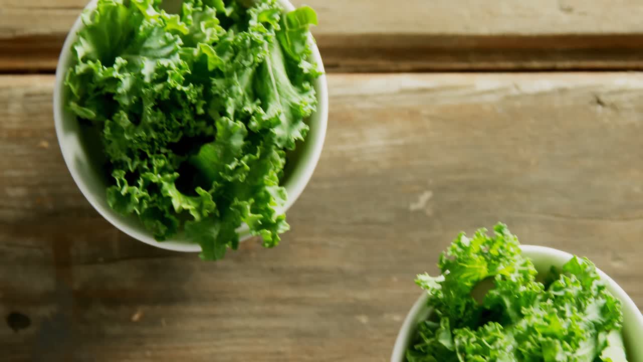 Green lettuce leaves in bowl placed on wooden table 4K 4k