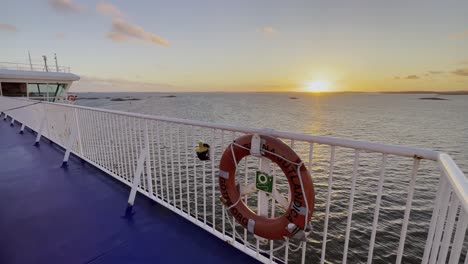 weißes geländer eines raumschiffs bei sonnenuntergang im meer mit kleinen steininseln mit rettungsboje