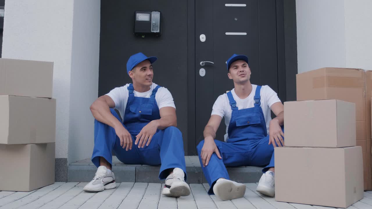 두 명의 이송 회사 노동자가 계단에 앉아 휴식을 취하고 있습니다.