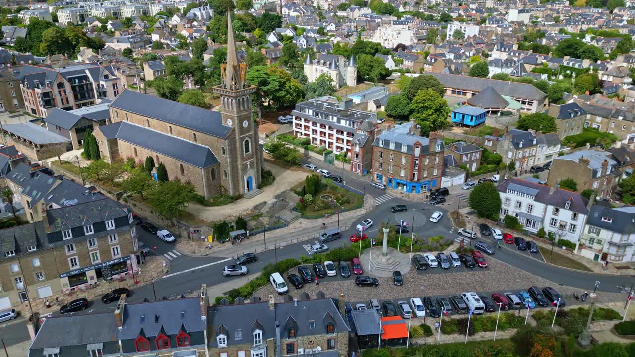 Notre Dame d'Emeraude church and Place Général de Gaulle in Dinard, historic architecture and town square with traffic, France. Aerial drone forward