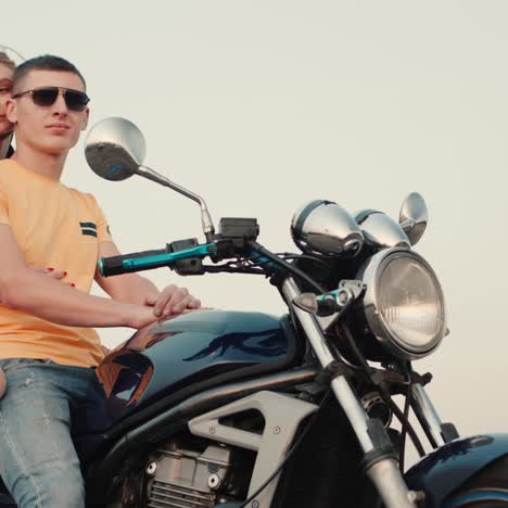 Romantic-couple-sit-on-a-motorcycle-and-admire-the-sunset-1