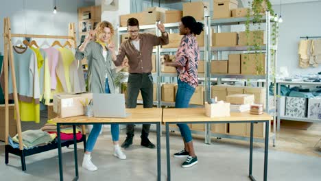 diseñadoras de ropa y sastre bailando en un taller divirtiéndose, sintiéndose feliz y celebrando la apertura de la tienda