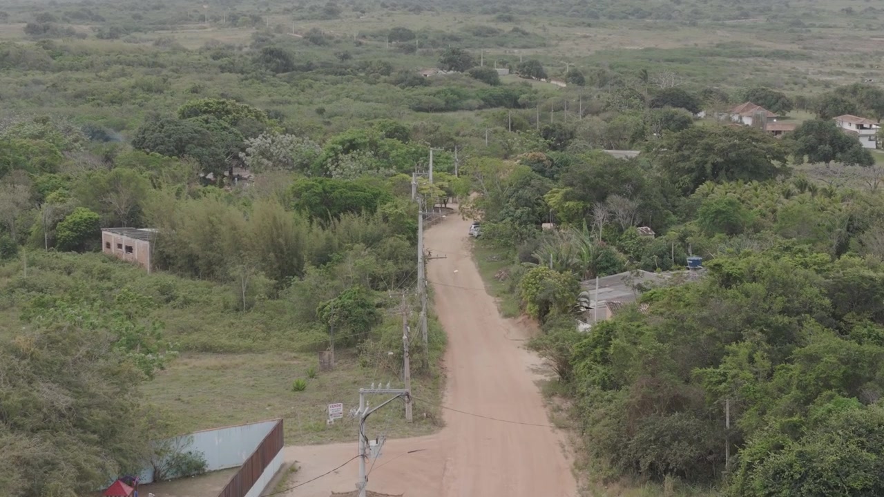 Luftfoto af en grusvej, der krydser grønne marker og spredte landhuse i Brasilien.