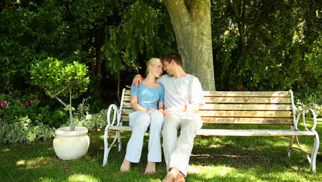 Happy-couple-sitting-down-on-park-bench-together