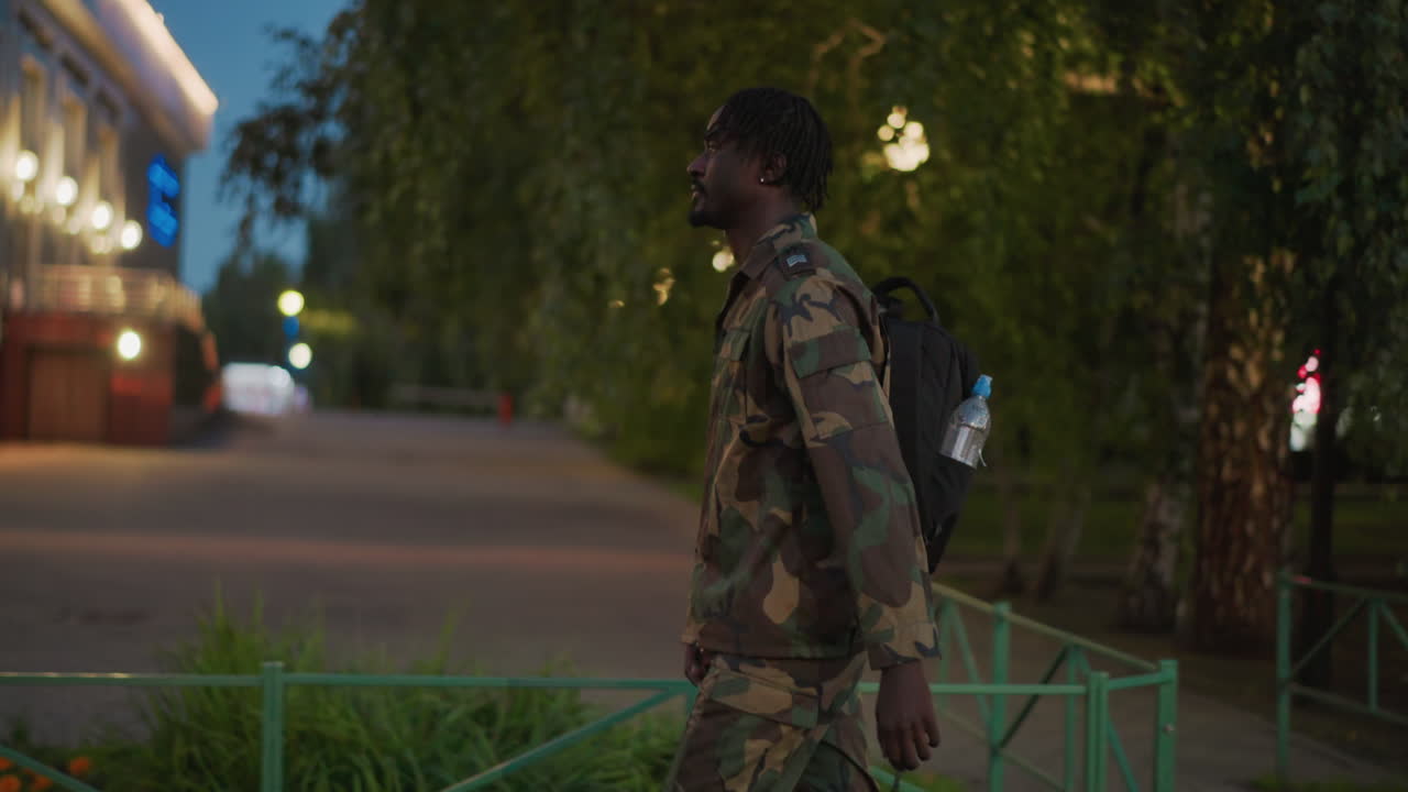 Night Watchman Pauses Silently Among Trees, Stealthy Soldier Halts Quietly Near Woodland Pathway At Night, Ambiguous Figure Remains Motionless Amid Evening Park Scenery With Silent Vigilance