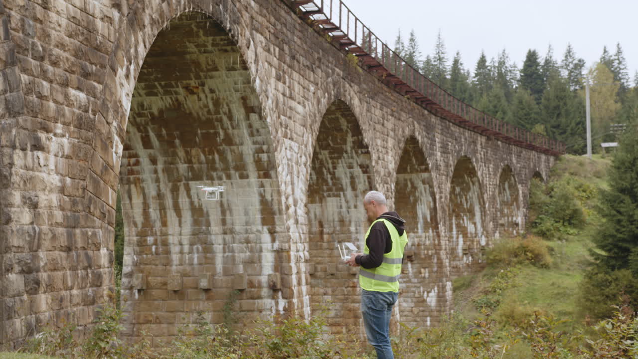 piloto de avión no tripulado inspeccionando un viejo puente de piedra en el bosque