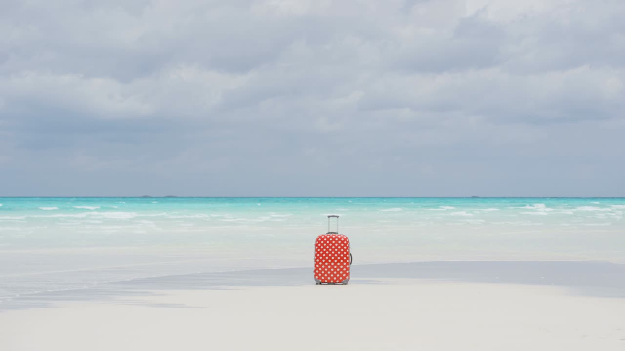 모래 해변 에 있는 다채로운 여행 가방