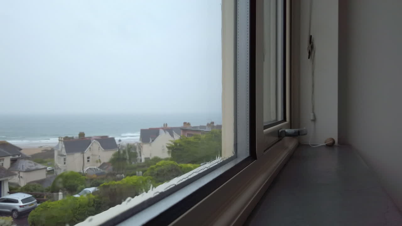 슬로우 모션으로 바다 전망을 감상할 수 있는 유리창 아래로 흐르는 비