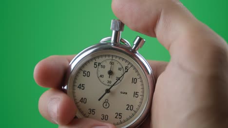 male hand holding analogue stopwatch on green screen chroma key. time start with old chronometer man presses start button in the sport concept. time management concept.