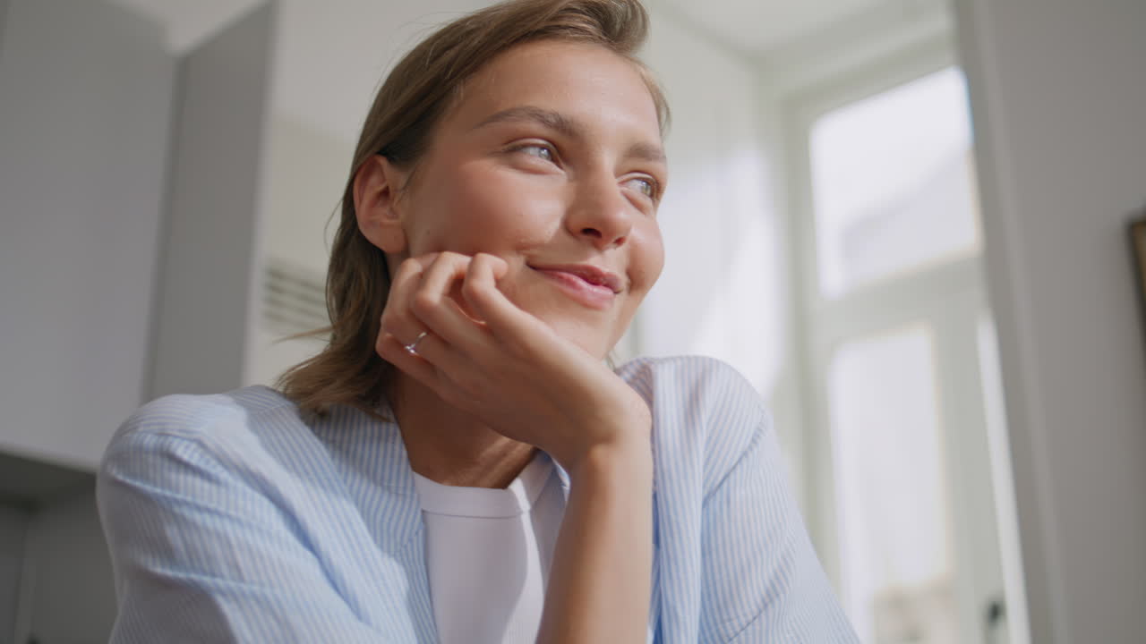 Relaxed lady messaging cellphone in sunny kitchen. Closeup pretty girl dreaming