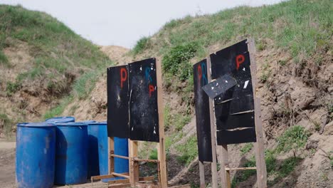 Blue-barrels-and-wooden-target-stand-at-Olesko-shooting-range-bay,-Czechia