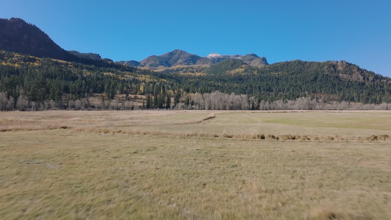 Expansive Colorado field with distant forested hills, calm outdoor scenery
