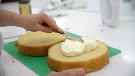 woman in bakery spreading filling for cake with knife