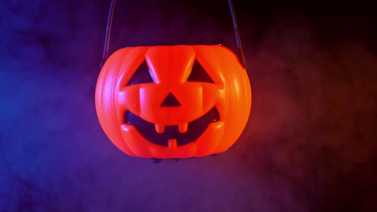 concepto de halloween - linterna de calabaza de plástico cerrando con humo azul-naranja alrededor aislado en fondo negro oscuro, aterrador y estado de ánimo de horror.