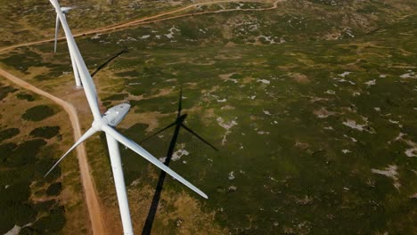 Aerial-orbiting-shot-of-a-wind-mill-in-a-windfarm-with-a-large-shadow