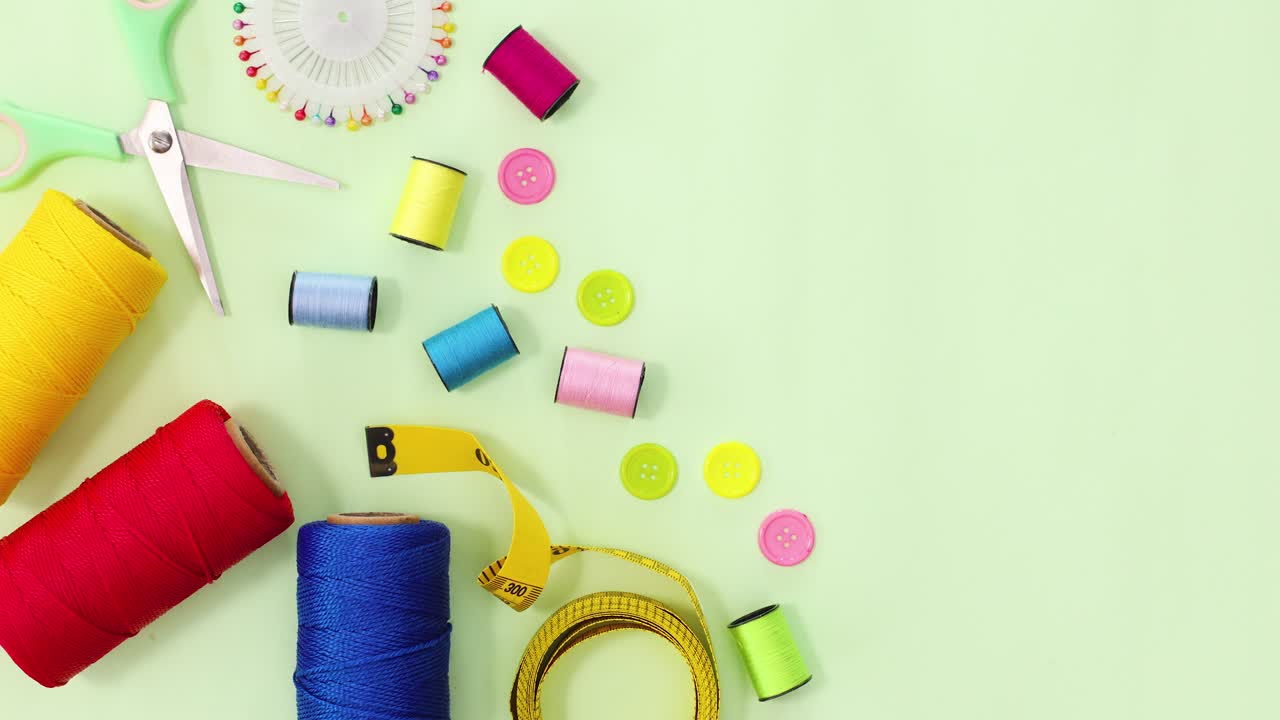 Sewing thread, scissors, buttons and pins move on green theme. Stop motion