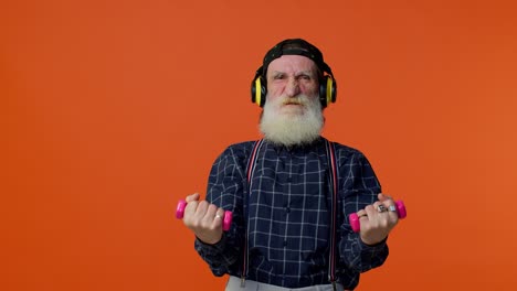 Senior-bearded-man-listening-music-via-headphones,-working-out,-lifting-pink-dumbbells,-healthcare