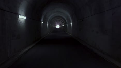 aerial flying through a long tunnel with light in the horizon