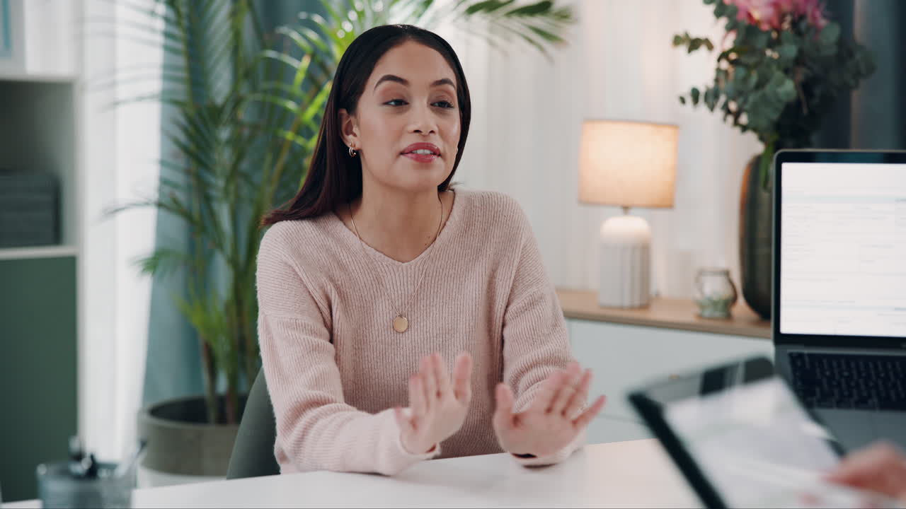 A woman sitting at a desk in an office talking to someone