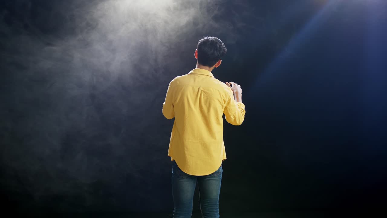 vista trasera de un niño con un micrófono y cantando sobre el fondo blanco de humo negro