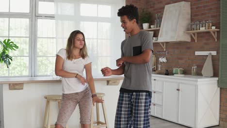 Morning-at-home-happy-young-couple-dancing-listening-to-music-in-the-kitchen-wearing-pajamas.-multi-ethnic-couple-in-love