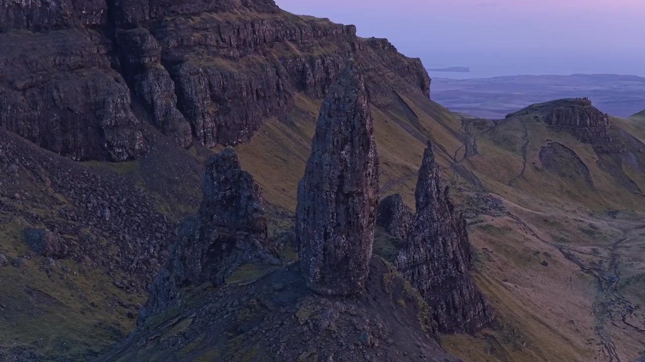 Majestätisk flygvy över Old Man of Storr, en berömd klippformation på Isle of Skye, Skottland, under en vacker lila soluppgång