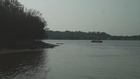 Un-Barco-Estacionario-Frente-A-La-Orilla-Del-Río-Mandovi-Rodeado-Por-El-Hermoso-Paisaje-Natural-A-Lo-Largo-De-La-Orilla-Del-Río,-Panjim,-India