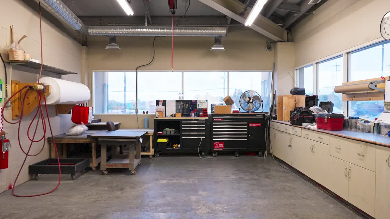 Wide slow-motion view shows woodworking workshop full of tools, hoses, and light