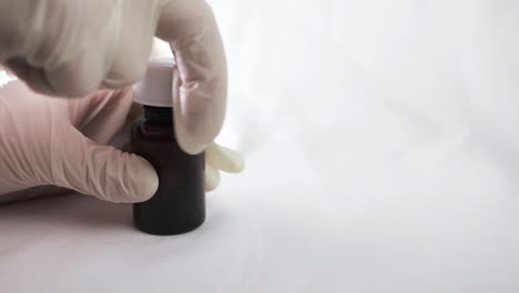 abriendo una botella de medicina con guantes blancos primer plano
