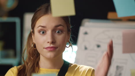 tired business woman grabbing head near stickers board in modern office.