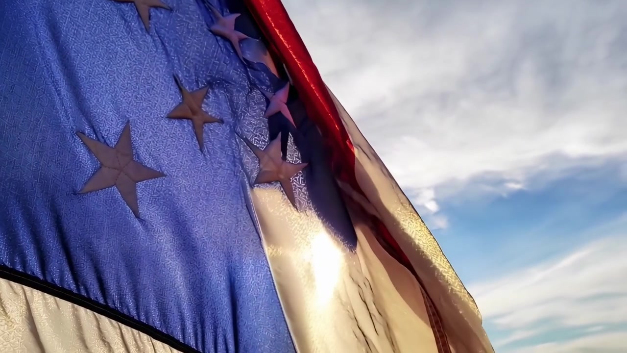 Bandera estadounidense ondeando contra un cielo azul brillante