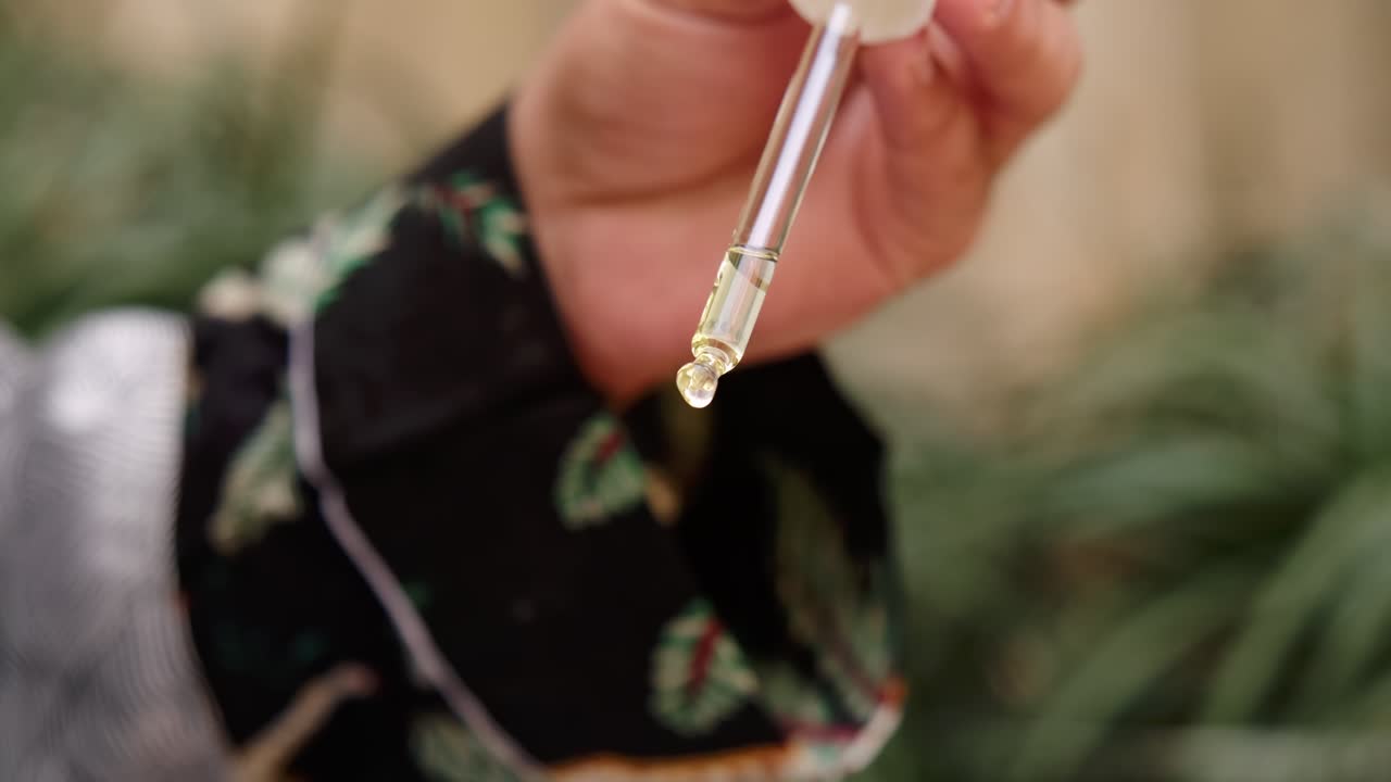 Close up of natural oil dripping slow motion from pipette. Organic cosmetics oil for hair, face and body.