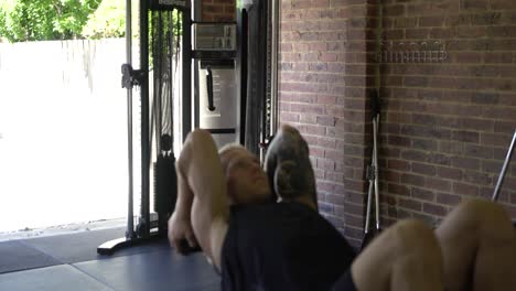 Tattoo-man-muscles-in-home-gym-doing-dumbbell-tricep-skull-crusher-blurry