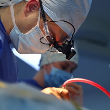 surgeon in glasses conduct a surgery. professional doctor in medical mask and special equipment performing an operation in clinic. health care concept