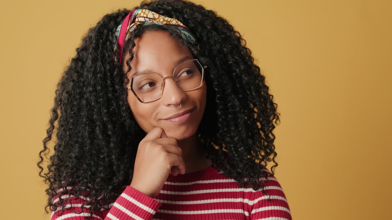 Thoughtful Young Woman with Curly Hair and Glasses Smiling
