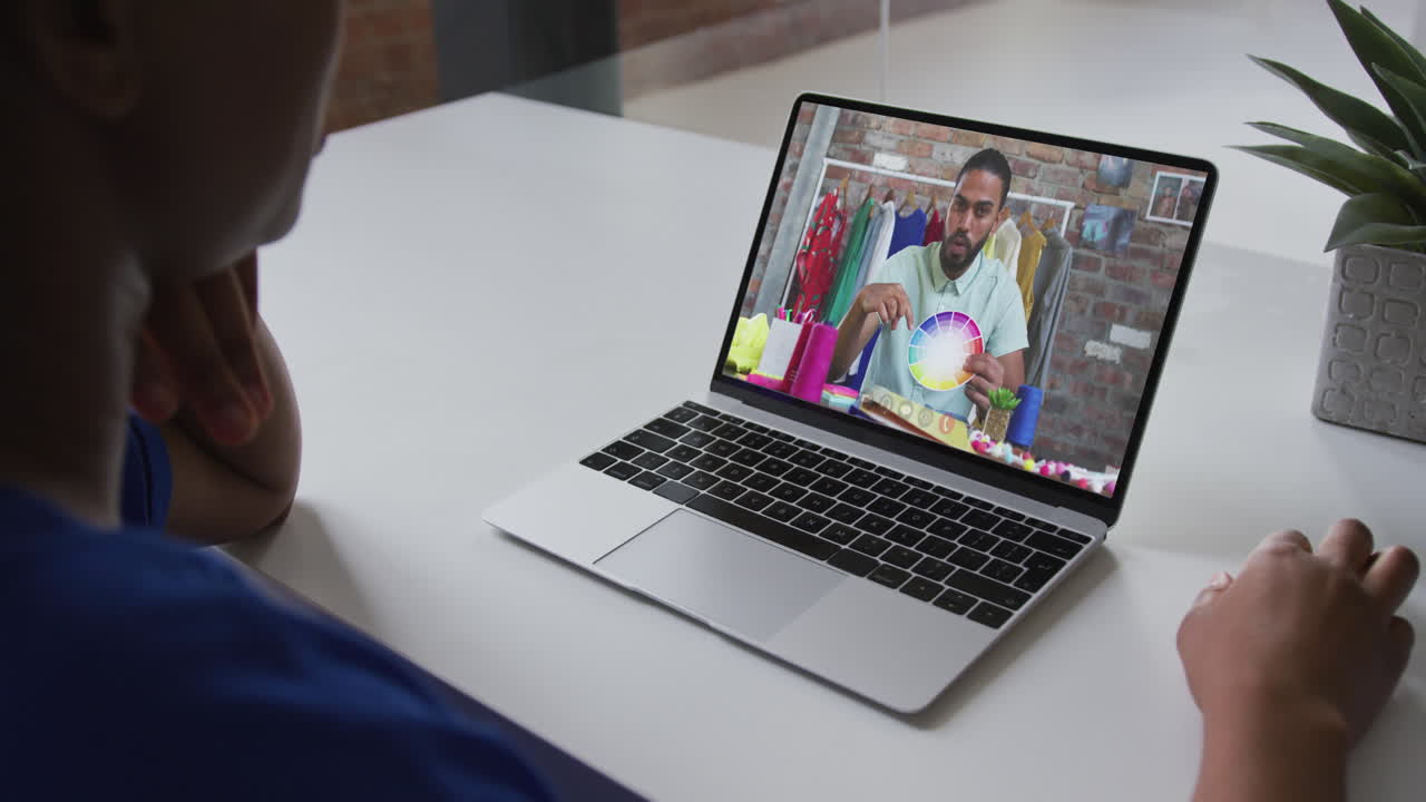 African american businesswoman sitting at desk using laptop having video call with male colleague