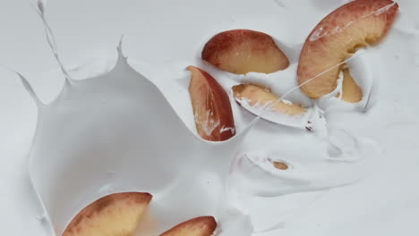 slices peach falling yogurt in super slow motion close up. natural breakfast.