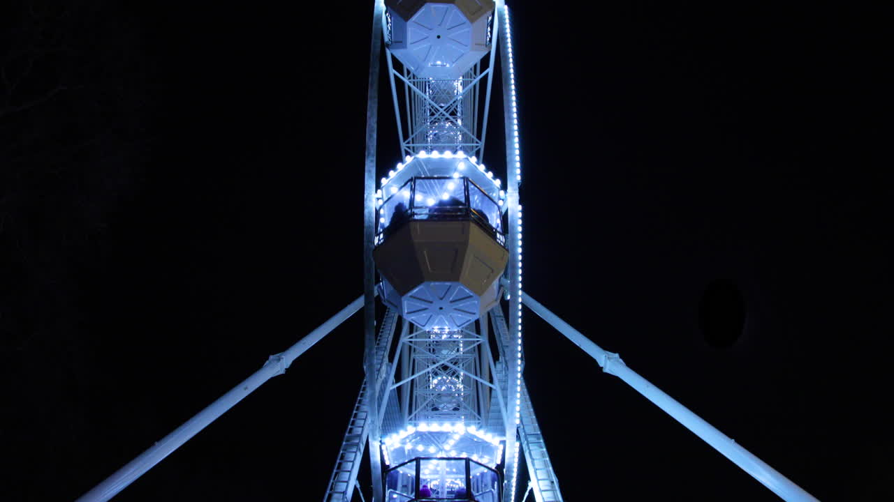 4k 60fps 느린 동작으로 캡처된 크리스마스 밤 동안 브르노에 있는 객실을 지배하는 대형 조명 철제 바퀴의 밑면