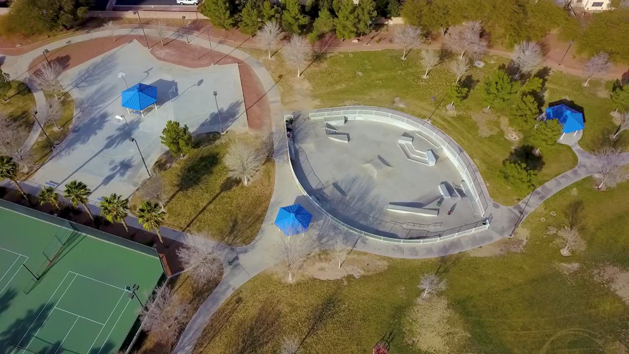 스케이트 공원, 인근 공원, 야자수, 테니스 코트에서 스케이트보드를 타는 아이들의 공중 전망