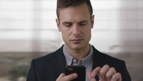 close-up-young-handsome-man-portrait-of-successful-business-entrepreneur-texting-browsing-using-smartphone-in-office-workspace-background